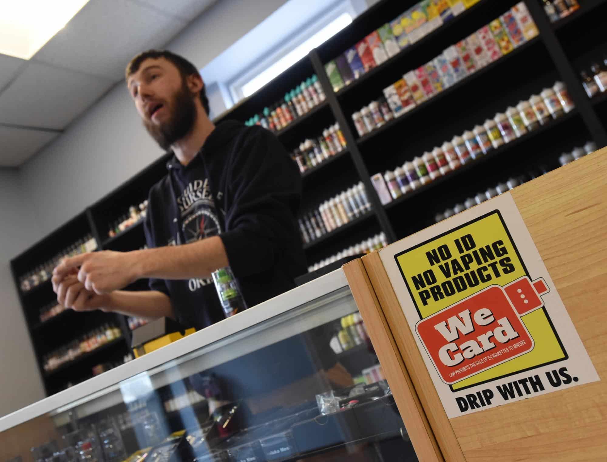 Vape shop clerk checking ID with we card sticker on counter